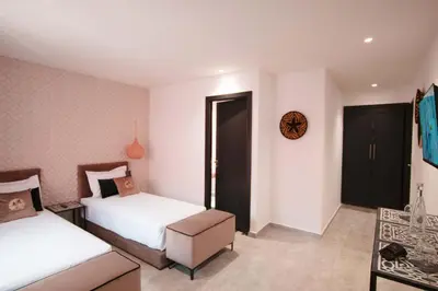 a bedroom with two beds and a table at Riad La Petite Majorelle in Marrakech