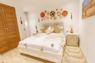 a bedroom with a white bed and a wooden door at Luxueux 138 m2 avec piscine in Marrakech