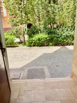 an open door to a courtyard with trees and bushes at Belle Appartement familiale,couple marié in Marrakech