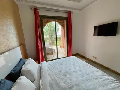 a bedroom with a bed and a tv and a window at Au Riad de la Palmeraie - Marrakech in Marrakech