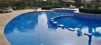 a man standing next to a large blue swimming pool at Prestigia Agate golf Piscine Marrakech in Marrakech