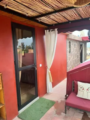 a red house with a glass door and a chair at Dar L'hna in Marrakech