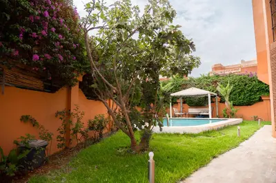 a garden with a tree and a swimming pool at villa 5 chambres pour famille avec piscine & parking in Marrakech