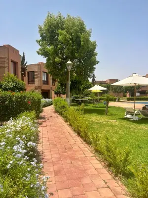 a brick walkway leading to a park with an umbrella at Luminous apartment with pool view in Marrakech