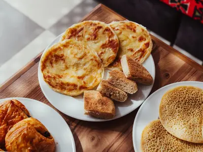a wooden table with plates of pancakes and bread at Dar Nourdha in Marrakech