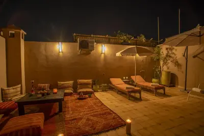 a living room with a couch and tables and an umbrella at Riad Tala in Marrakech