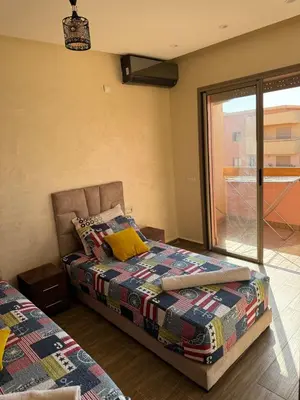 a bedroom with a bed with a quilt and a window at Bel appartement à louer à Marrakech targa in Marrakech