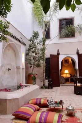a courtyard of a house with a table and pillows at Riad Dar Rania Marrakech Médina Jemaa El Fna in Marrakech