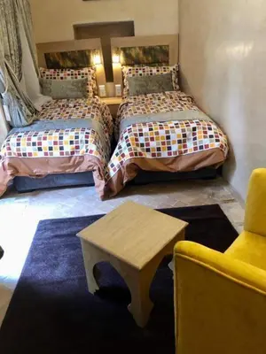 a bedroom with two beds and a table and a chair at Riad Dar Rania Marrakech Médina Jemaa El Fna in Marrakech