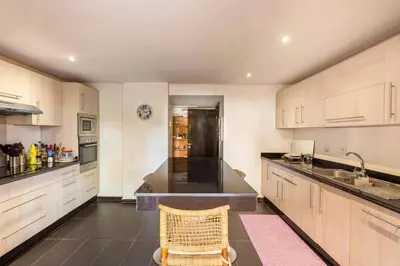 a large kitchen with white cabinets and a chair in it at Somptueux Duplex au coeur de l'Hivernage in Marrakech