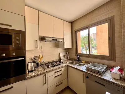 a kitchen with white cabinets and a sink and a window at Prestigia Luxury Appart 2 Room in Marrakech