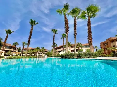 a large swimming pool with palm trees in the background at Prestigia Luxury Appart 2 Room in Marrakech