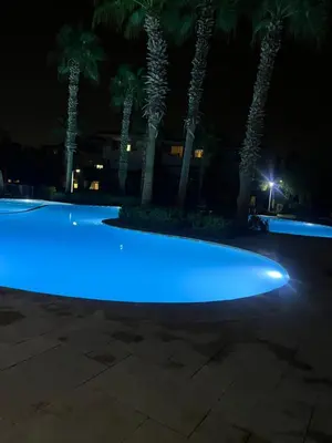 a pool with blue lights in front of palm trees at Prestigia Luxury Appart 2 Room in Marrakech