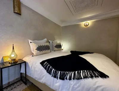 a bedroom with a bed with a black and white blanket at Riad Citrus By La Siredrah in Marrakech