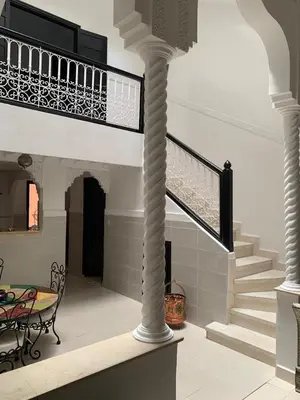 a spiral staircase in a house with a table and chairs at Riad lalla aicha in Marrakech