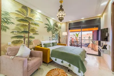 a bedroom with a bed and a couch and a tv at L'Atlas - Appartement Authentique à Gueliz in Marrakech