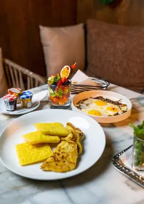a table with plates of breakfast food on it at Hotel Le Rocher Marrakech in Marrakech