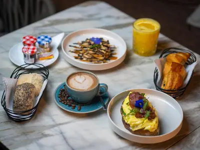 a table with plates of breakfast foods and a cup of coffee at Hotel Le Rocher Marrakech in Marrakech