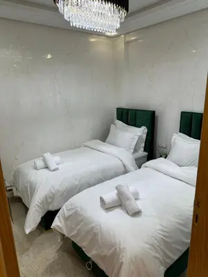 two beds in a room with white sheets and towels at Modern-elegant Appartement in het centrum in Marrakech