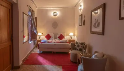 a bedroom with a bed and a couch and chairs at Riad Anais Marrakech in Marrakech