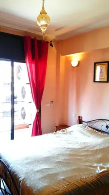 a bedroom with a large bed with a red curtain at Votre appartement d'exception in Marrakech