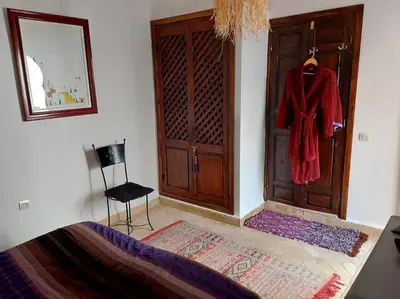 a bedroom with a bed and a door with a red robe at Riad Sophora - Peaceful Heaven in Marrakech in Marrakech