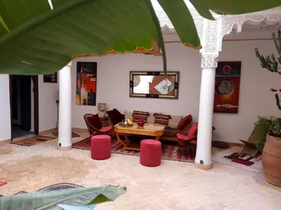 a living room with a table and red chairs at Riad Sophora - Peaceful Heaven in Marrakech in Marrakech