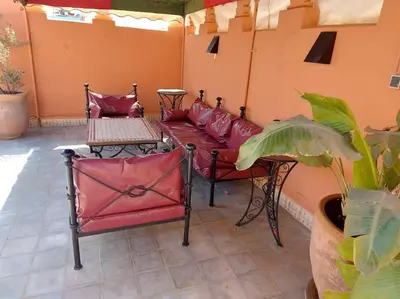 a patio with a red couch and tables and a plant at Riad Sophora - Peaceful Heaven in Marrakech in Marrakech
