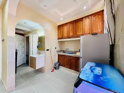 a kitchen with wooden cabinets and a refrigerator at Famille Hanae appartement avec terasse in Marrakech