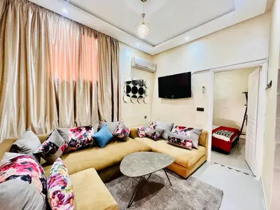 a living room with a couch and a tv at Famille Hanae appartement avec terasse in Marrakech