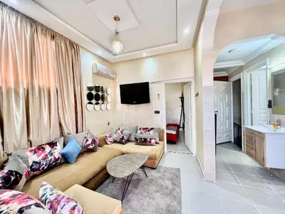 a living room with a couch and a tv at Famille Hanae appartement avec terasse in Marrakech