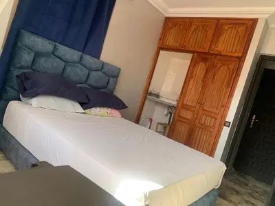 a bedroom with a bed with a blue headboard and a mirror at Familiale Chambre calm wifi Hanae in Marrakech