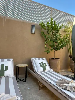 a patio with two beds and a potted plant at Riad Kamilyes in Marrakech