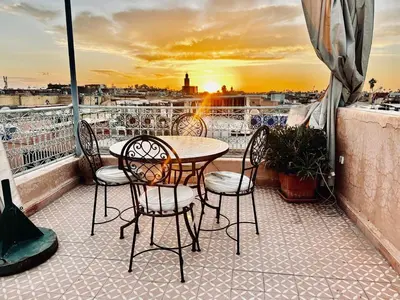a table and chairs on a balcony with a sunset at Riad Radia in Marrakech