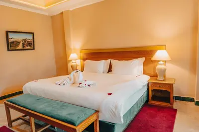 a bedroom with a large white bed and a bench at Palais Jena in Marrakech