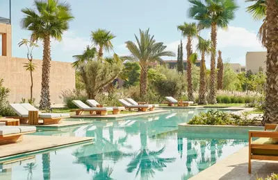 a pool with lounge chairs and palm trees at Park Hyatt Marrakech in Marrakech