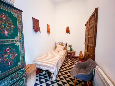a small room with a bed and a dresser at Riad Amethyste in Marrakech