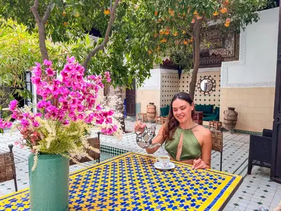 a woman sitting at a table with a cup of coffee at Riad Amethyste in Marrakech