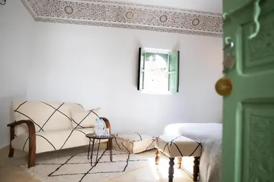 a white bedroom with a bed and a table at Riad Chic in Marrakech