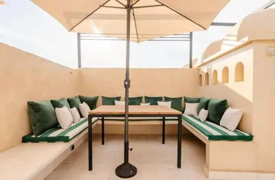 a table and benches with an umbrella on a balcony at Riad Manzal in Marrakech
