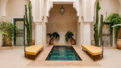 a swimming pool in a building with two beds and cactus at Riad Manzal in Marrakech