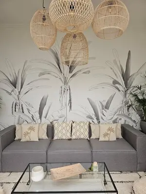 a living room with a gray couch and palm wallpaper at Riad Coconut in Marrakech