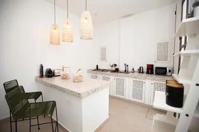 a kitchen with white walls and a counter and chairs at Riad Coconut in Marrakech