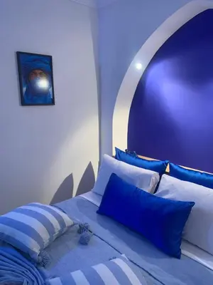 a bedroom with a bed with blue and white pillows at Riad Le Roy’s in Marrakech