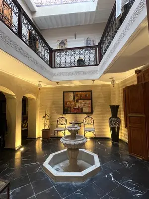 a large lobby with a fountain in the middle of a room at Riad Le Roy’s in Marrakech