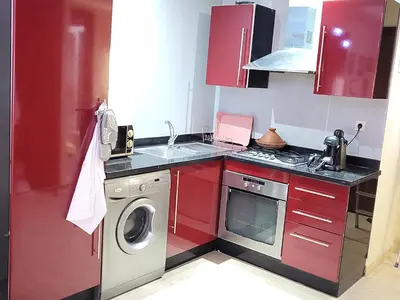 a kitchen with red cabinets and a washing machine at hamza in Marrakech