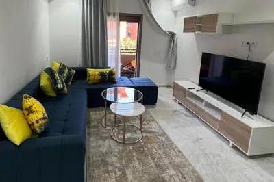 a living room with a blue couch and a tv at 1 Bed Apartment - Balcony Wifi Parking in Marrakech
