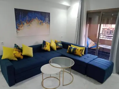 a blue couch with yellow pillows and a table at 1 Bed Apartment - Balcony Wifi Parking in Marrakech