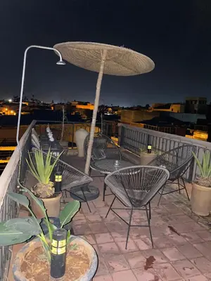 a patio with tables and chairs and an umbrella at MAISON PROCHE DANS LA MEDINA MARRAKECH in Marrakech