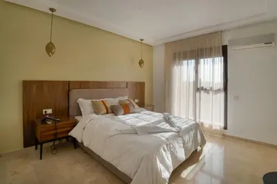 a bedroom with a large bed with a wooden headboard at Aya Suites in Marrakech